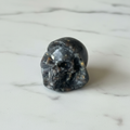 Teschio Santa Muerte Yooperlite - flatlay su marmo
