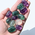 Mano che tiene fluorite arcobaleno tumbled