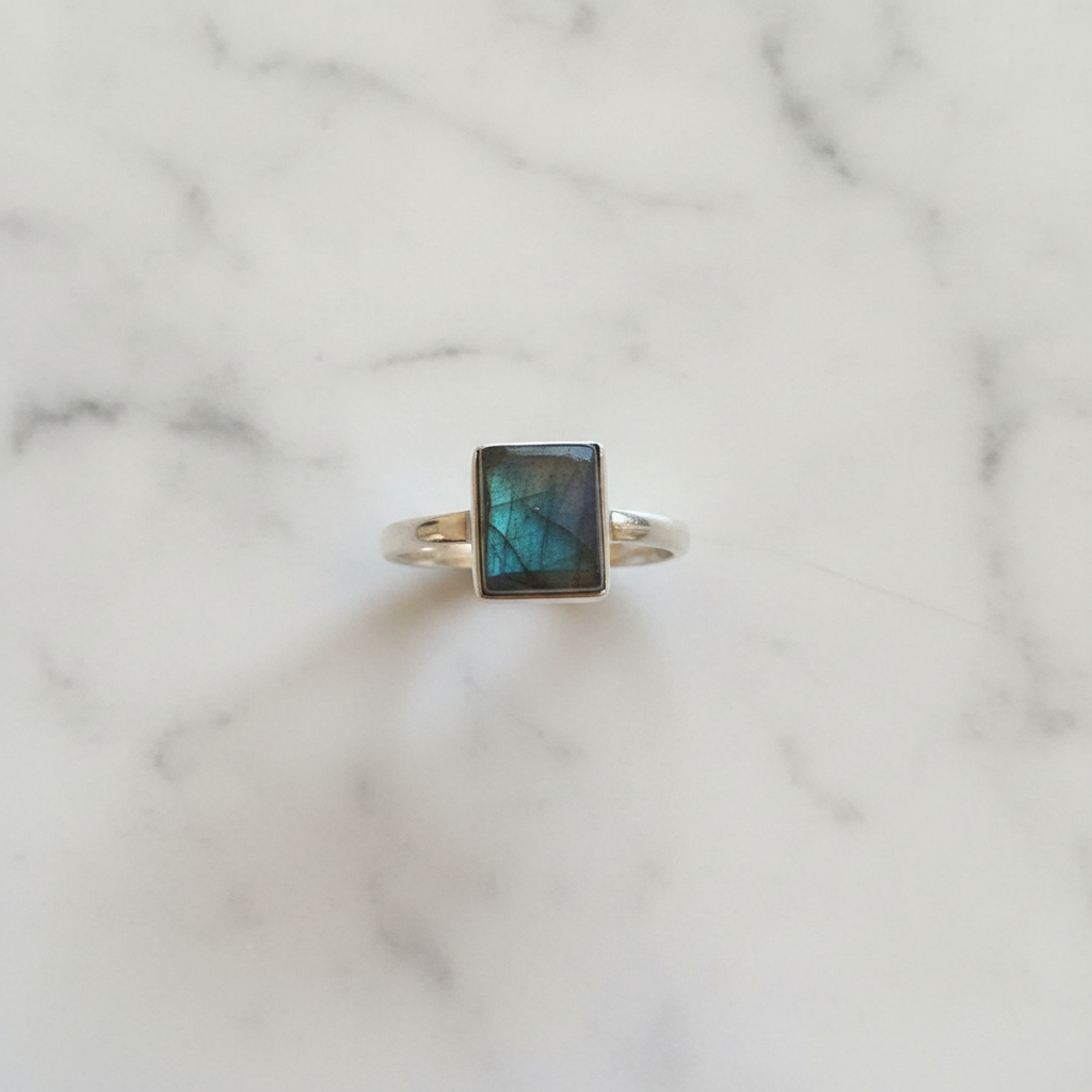 Anello labradorite verde argento flatlay su marmo