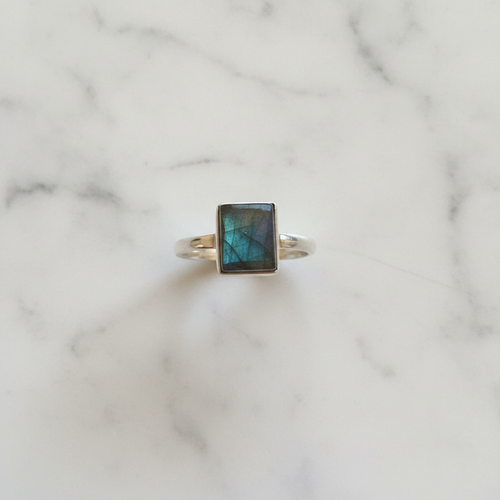 Anello labradorite verde argento flatlay su marmo