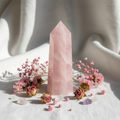 Obelisco quarzo rosa su lino con fiori e cristalli