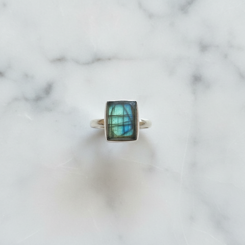 Anello labradorite verde argento flatlay su marmo