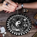 Mani con pendolo ossidiana sul tappetino zodiacale