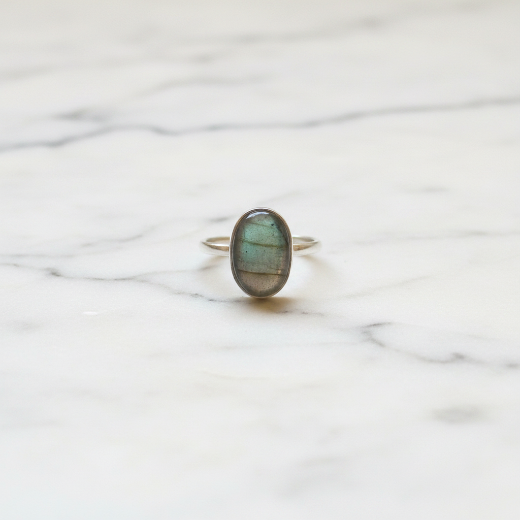 Anello labradorite verde argento flatlay su marmo