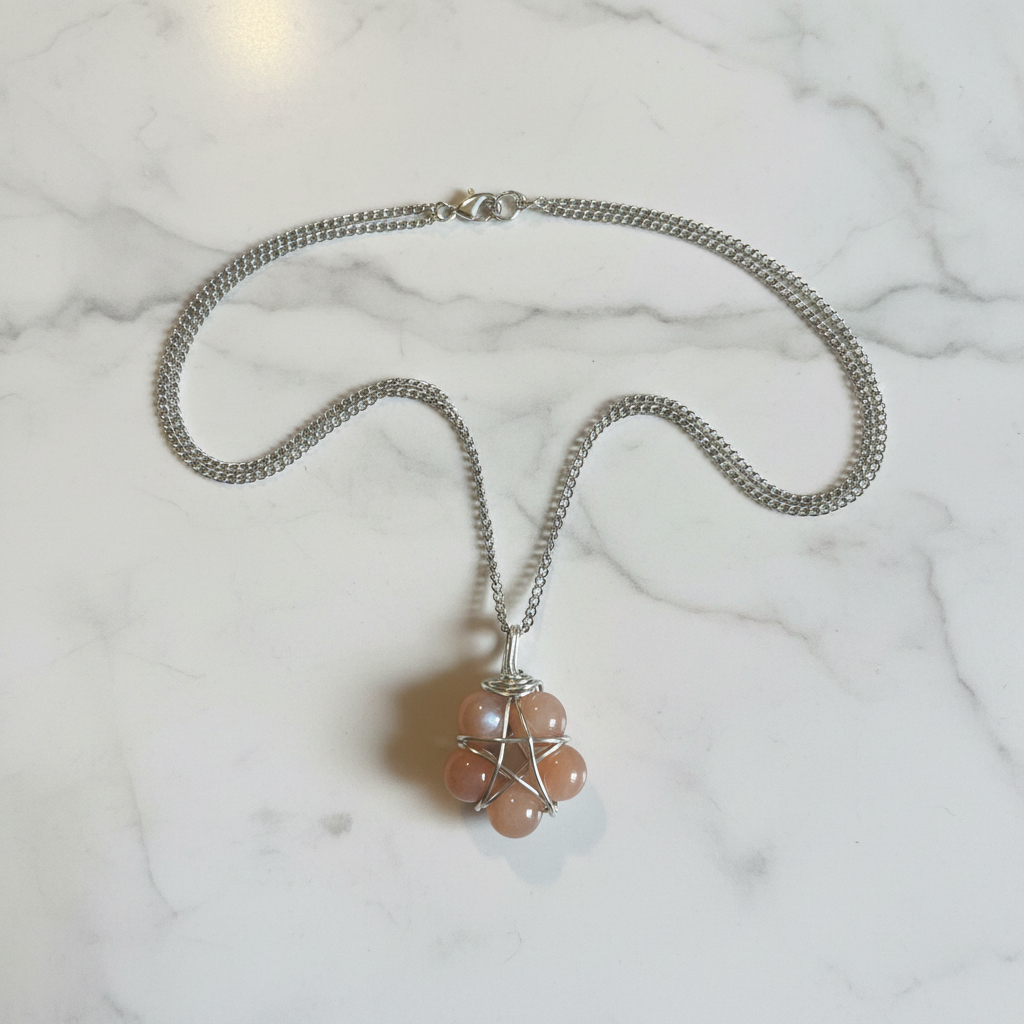Collana Pentacolo Pietra di Luna Pesca - flatlay su marmo