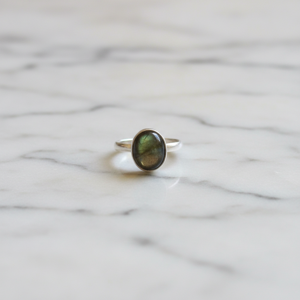 Anello labradorite verde argento flatlay su marmo