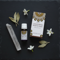 Olio aromatico Goloka California White Sage - flatlay su ardesia scura con salvia e fiori bianchi