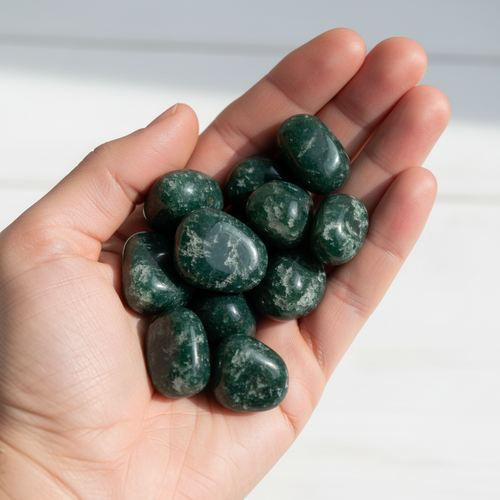 Pietre burattate di agata muschiata verde scuro tenute in mano aperta